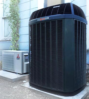 one ductless outdoor system next two an large outdoor central air condenser at a residential property