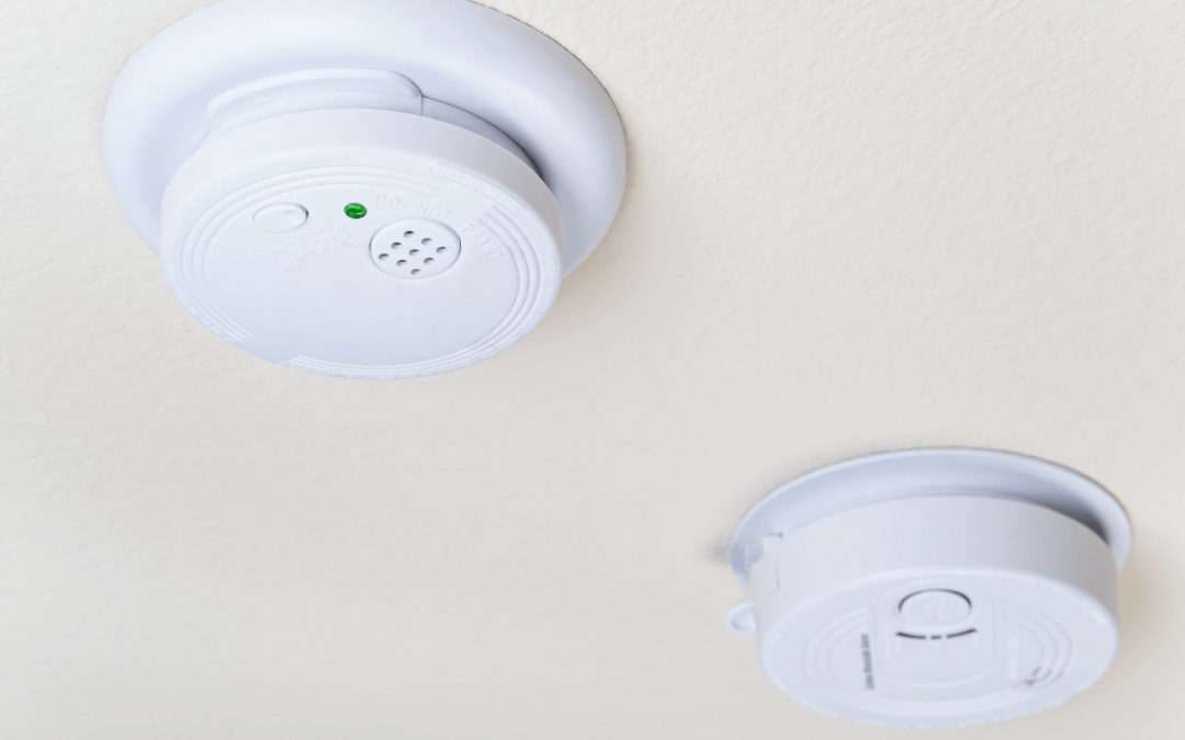 beige colored ceiling that has a smoke detector and a carbon monoxide alarm both in white.