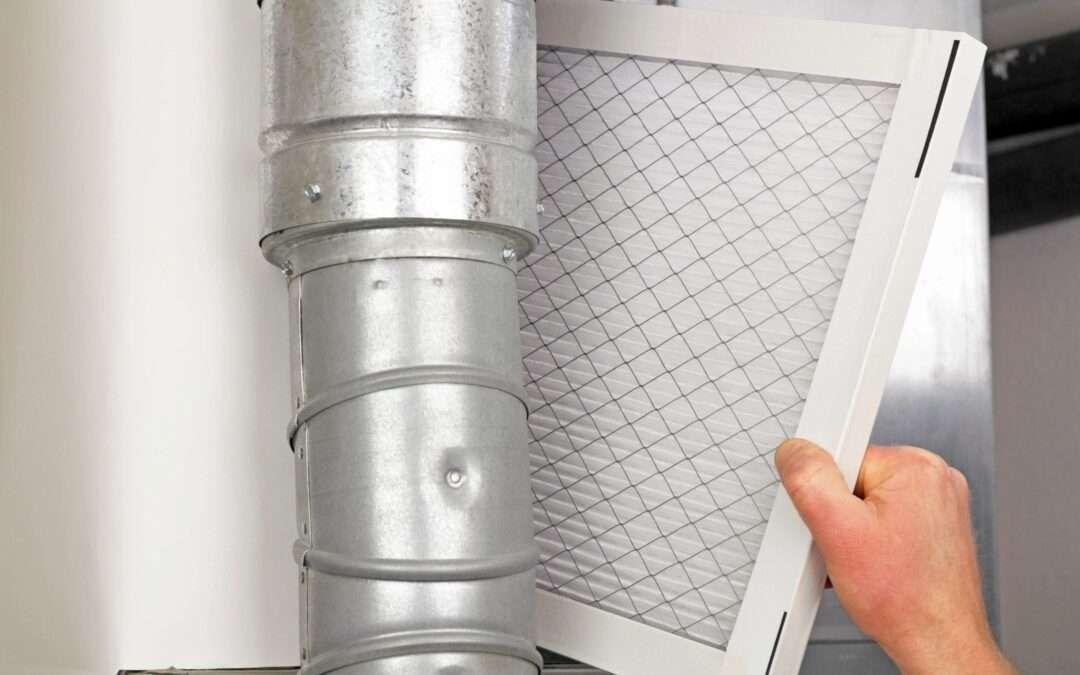 person reaching a pleated HVAC air filter behind a metal duct