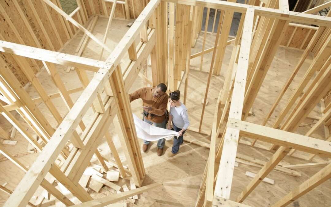 two people standing in the middle of a new home construction project looking at blueprint plans