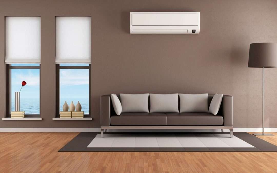 mini-split system installed in a living room with brown walls, a brown and gray couch, a brown lamp, and a brown and beige rug on wood floors, mini-split system used to cool a room that can be a hot spot